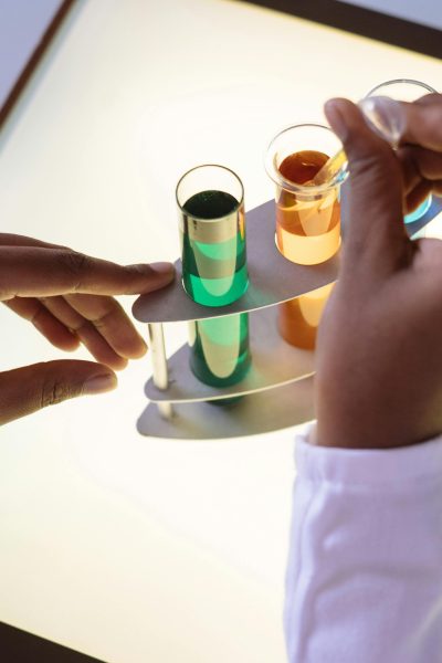 Crop laboratory technician in white uniform using pipette for taking sample from test tube during biochemical experiment in researching center